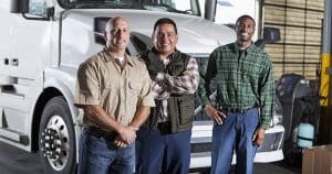 Three men standing in front of a semi-truck
